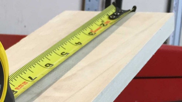 Tape measure being used to measure the linear feet of a board