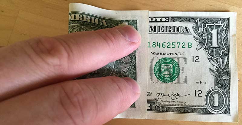 Fold the dollar bill with the left edge aligning between the N and O in the word "note"