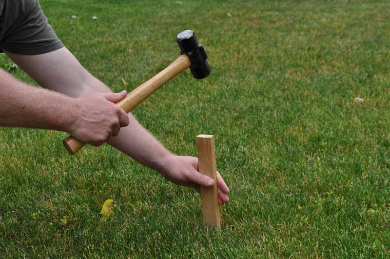 Fence installer pounding a layout stake into the ground