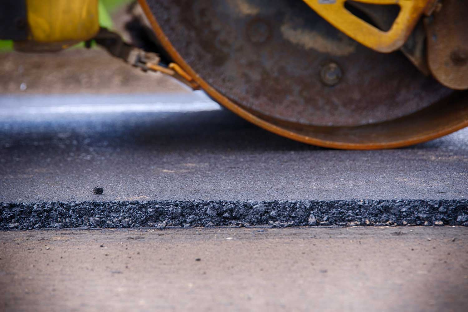 Steamroller compacting and flattening a new asphalt driveway