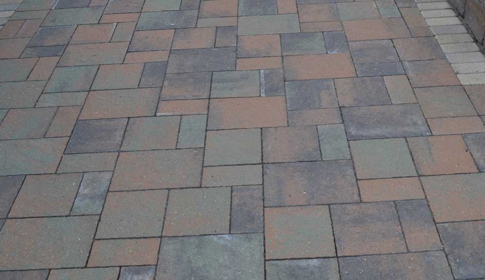 Paver patio constructed using concrete pavers in various colors, shapes, and sizes