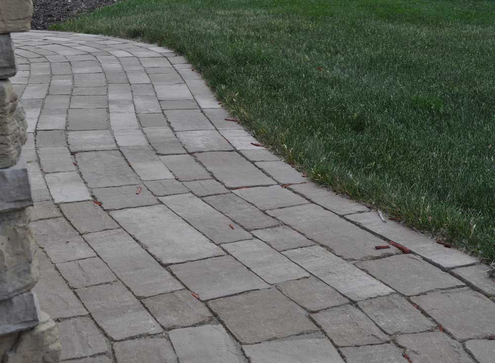 Winding paver walkway constructed using concrete pavers in various textures, shapes, and sizes