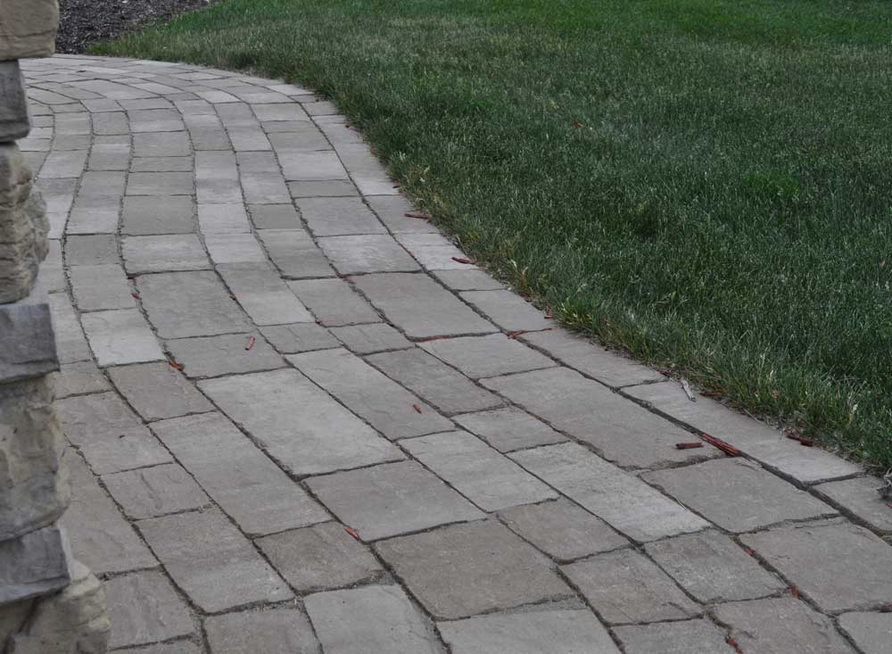 Winding paver walkway constructed using concrete pavers in various textures, shapes, and sizes