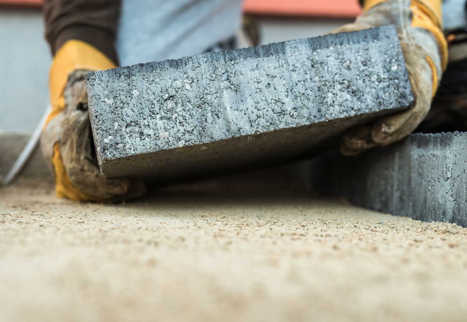 Person installing a paver patio on a newly laid paver base