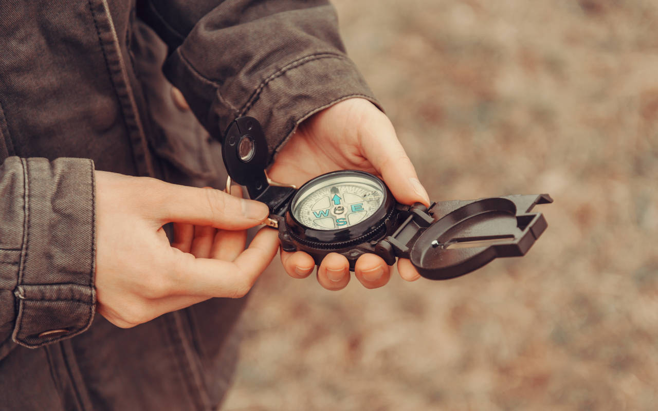 Person holding a compass to locate property lines defined in a deed's legal description