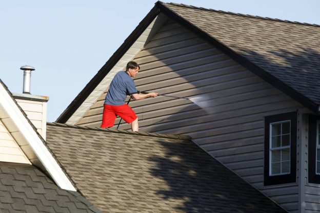 Man power-washing the siding of a home.