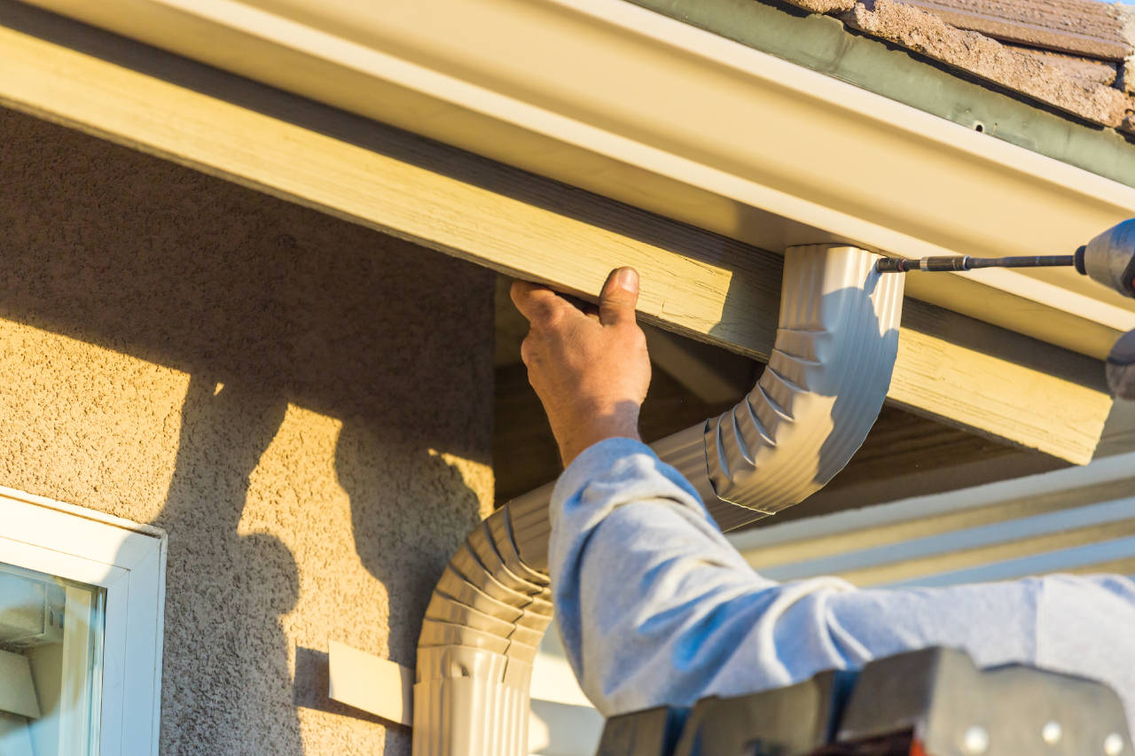 Installer attaching gutter downspout