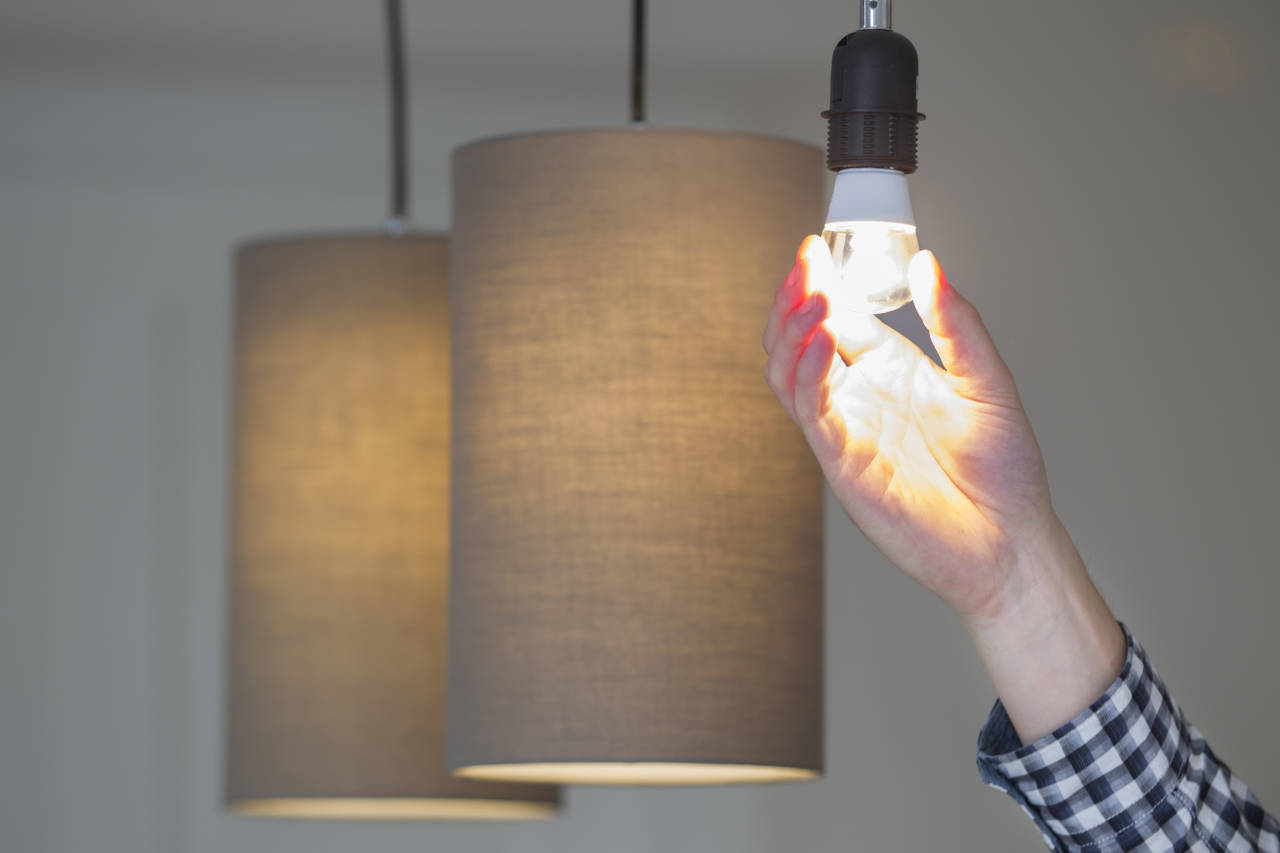 Person installing an LED light bulb in a pendant light fixture