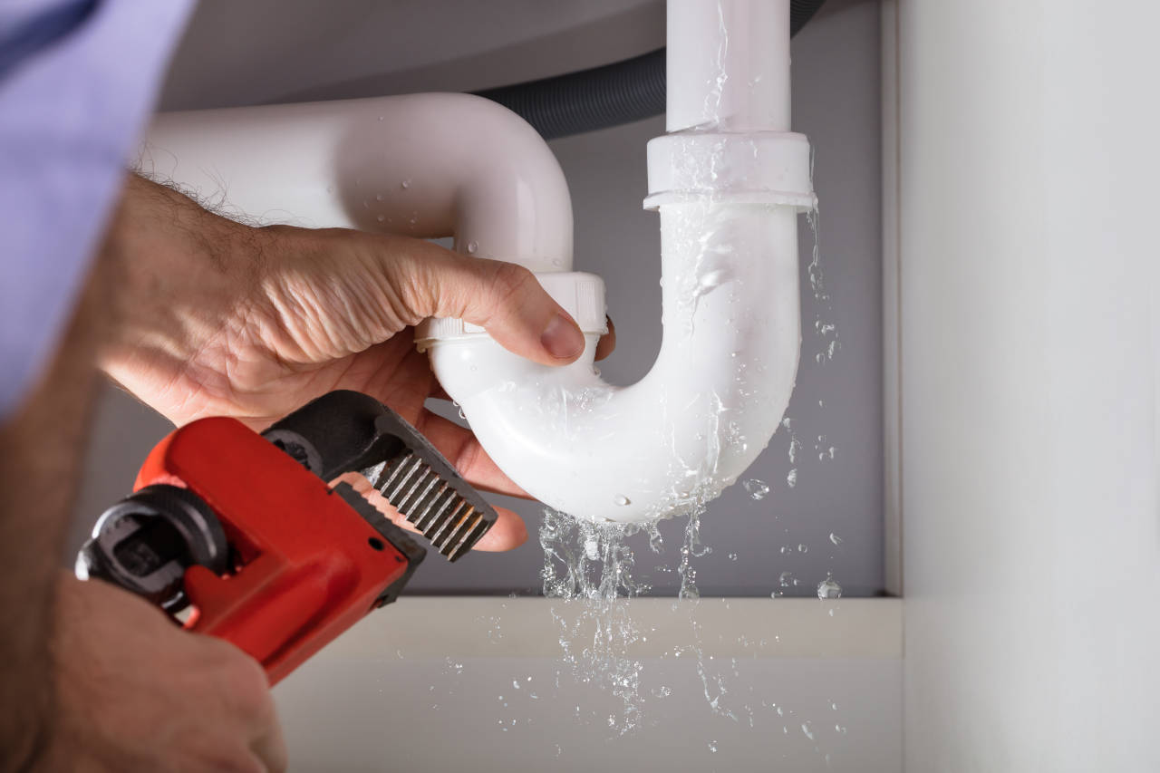 plumber fixing a drain pipe under a sink