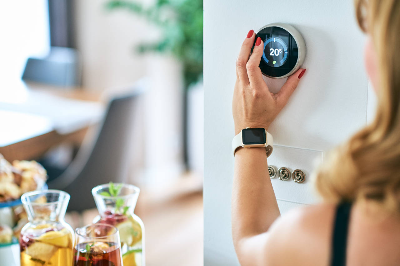 woman adjusting a Nest smart thermostat