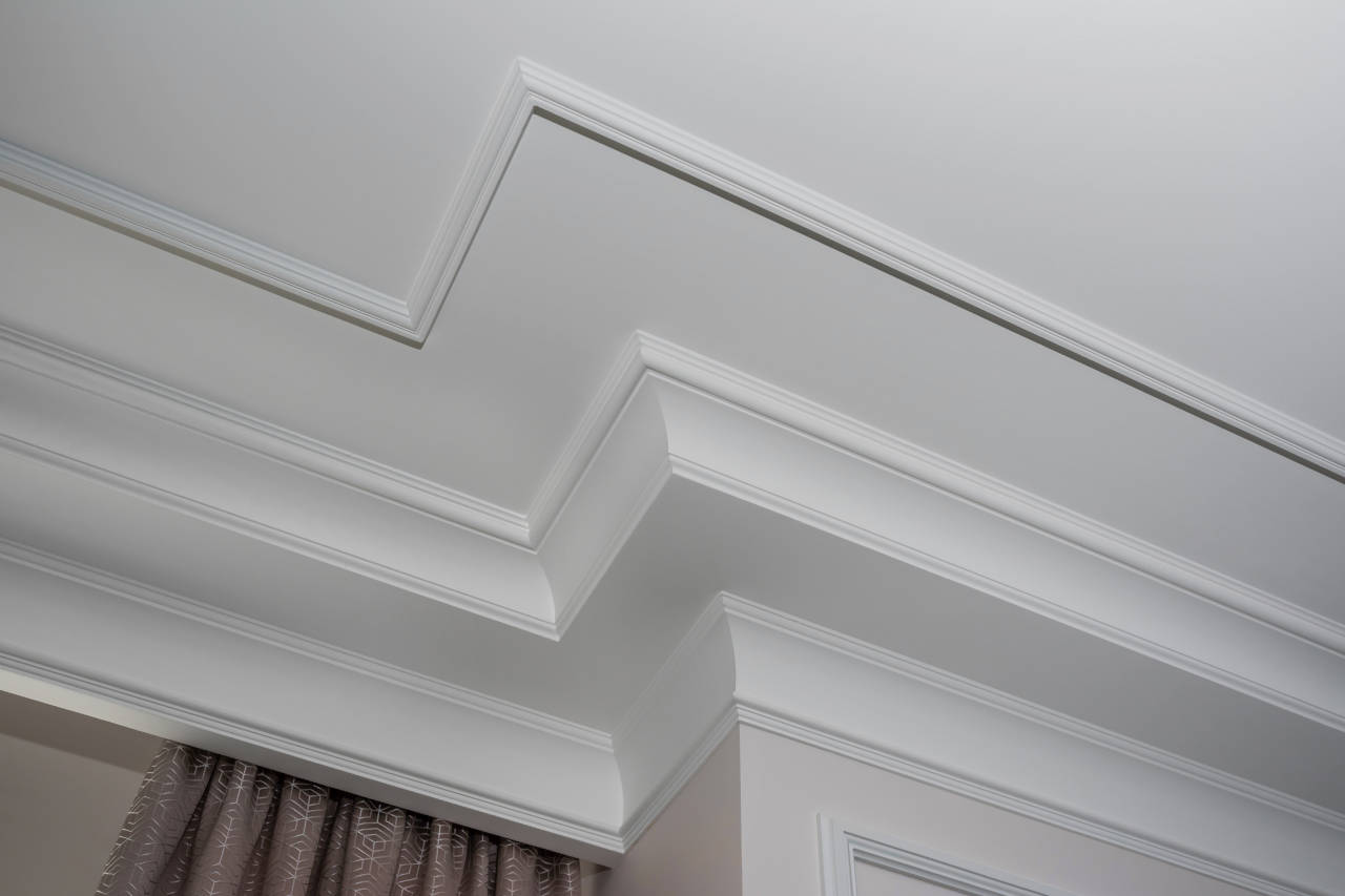 Crown molding installed near a window curtain pocket composed of several layers of trim