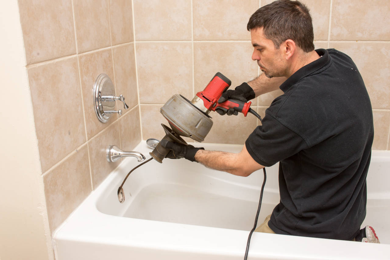 plumber clearing a clogged drain using a snake