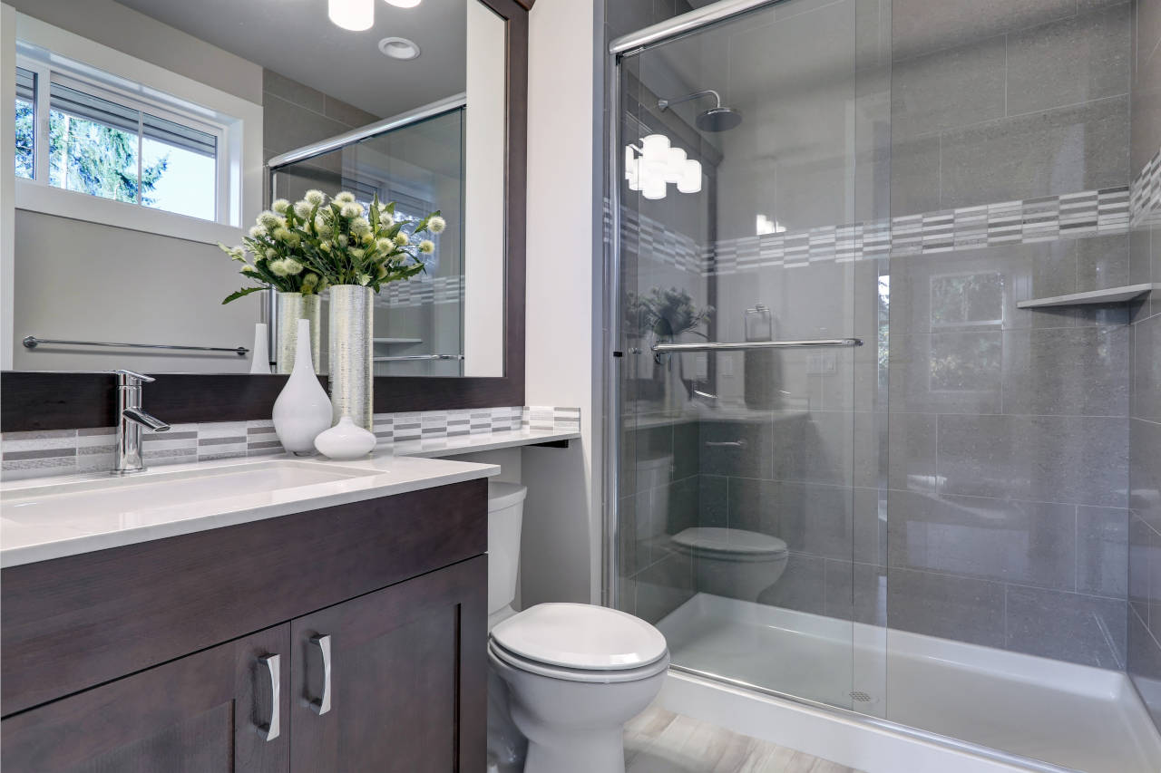 newly remodeled bathroom with dark wood vanity and custom tile shower