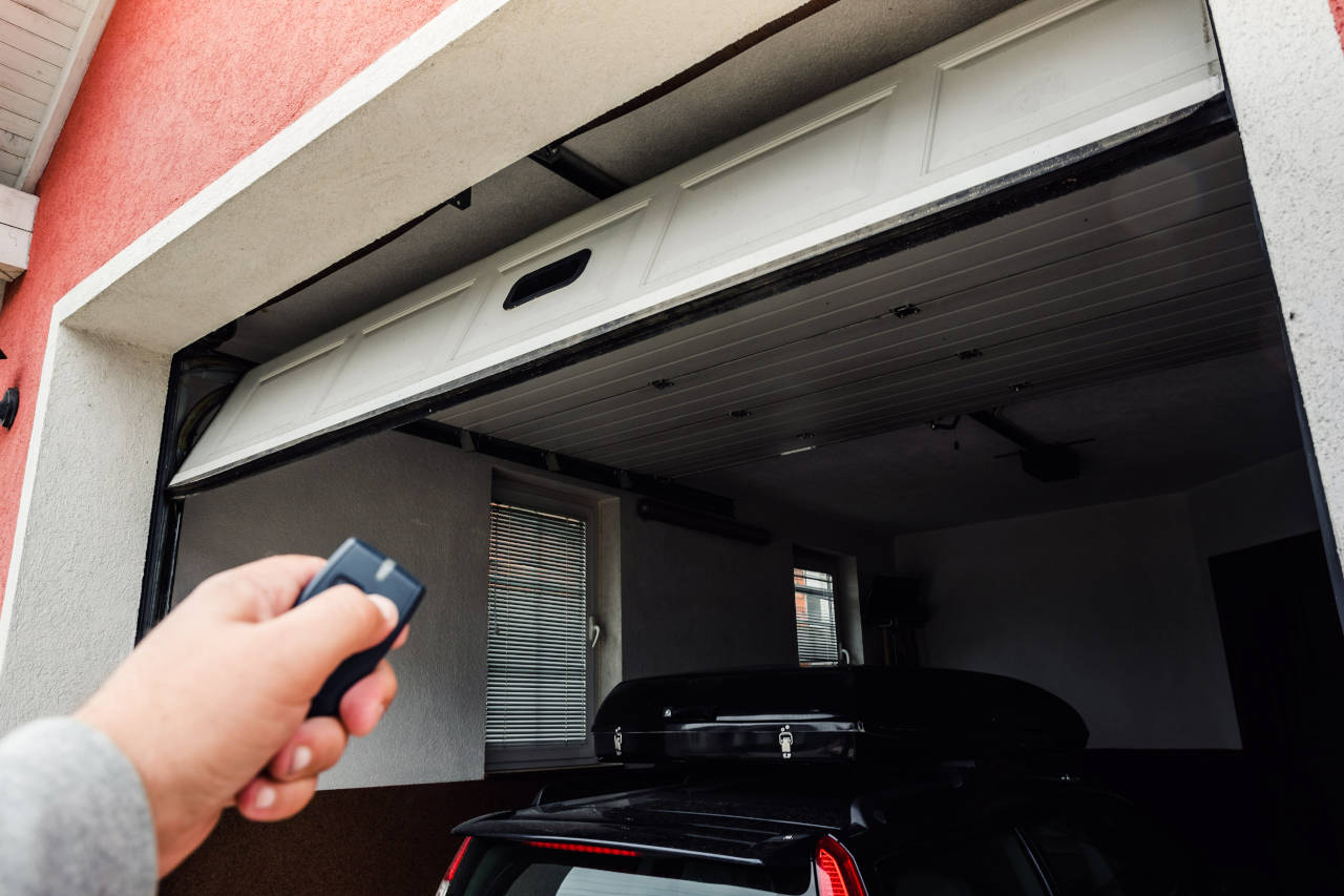 person opening garage using a garage door opener remote