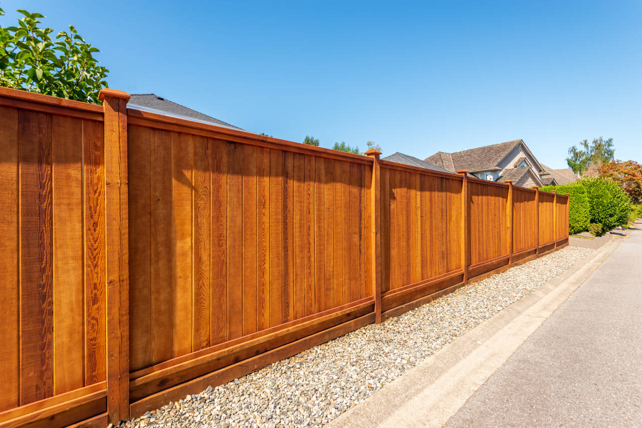 Newly installed wood privacy fence with dark red/brown stain