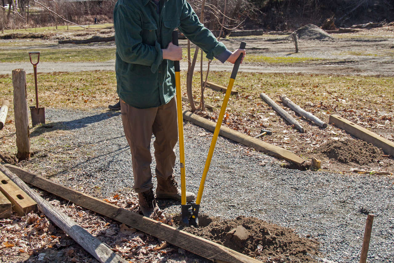 man digging post holes to install a new fence