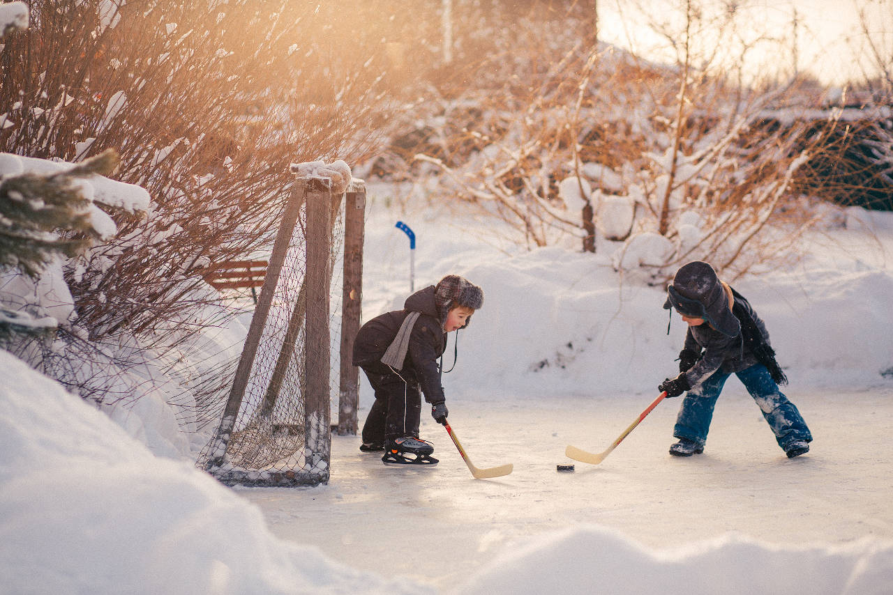 Kids playing hockey on a backyard ice rink