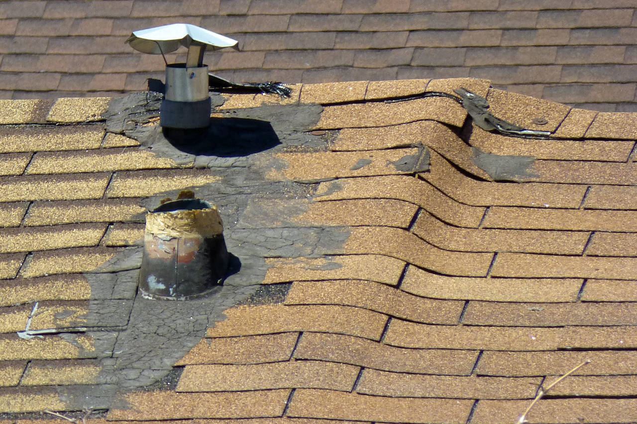 roof showing a significant buckle with a shingle separating