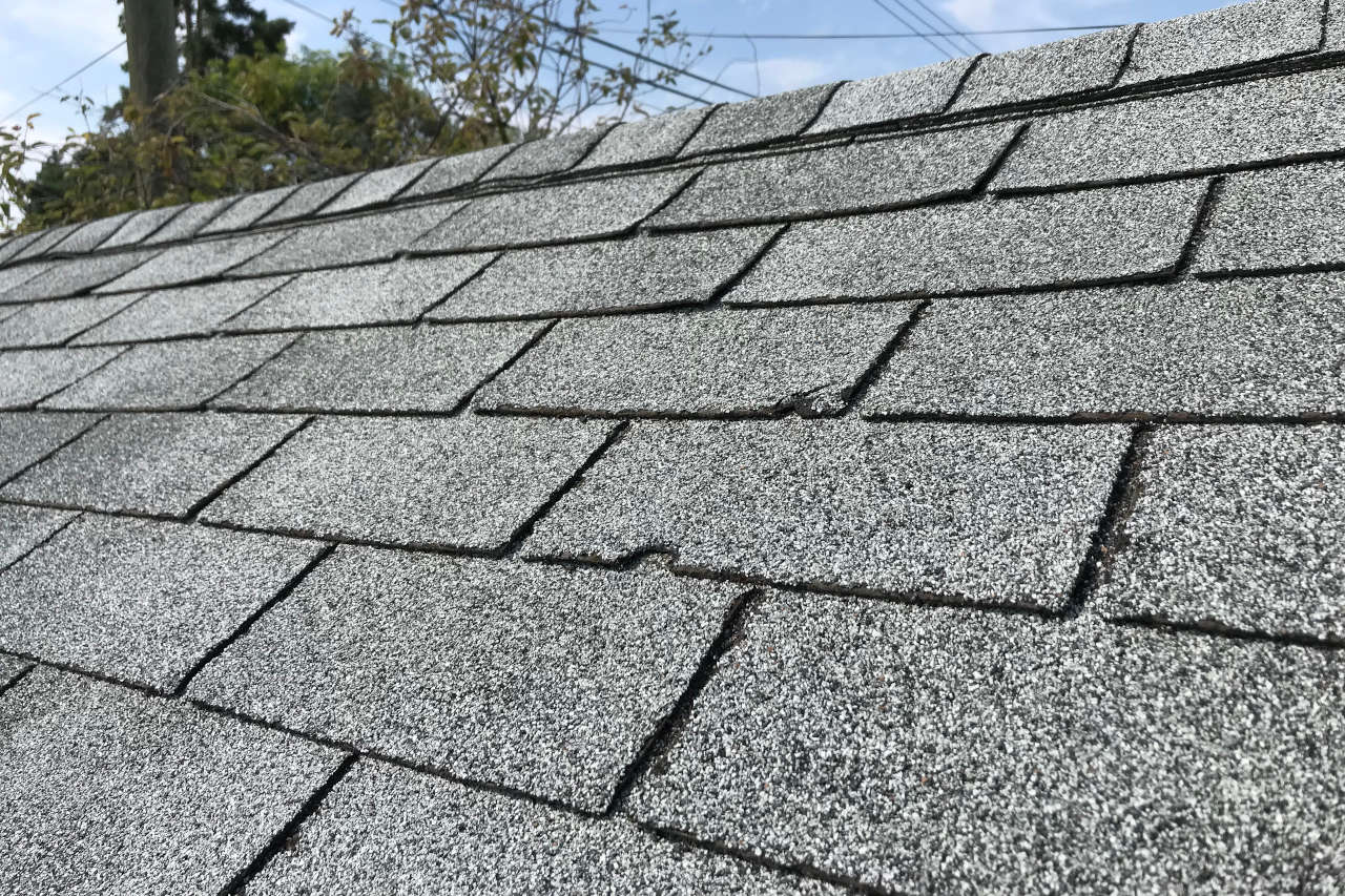 asphalt shingles with large cracks on an old roof in need of repair