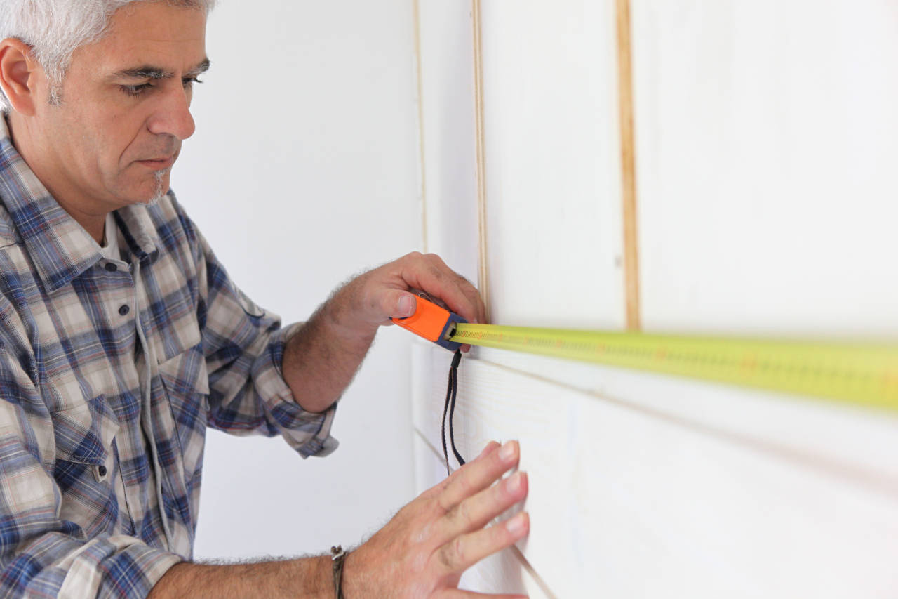 Homeowner using a tape measure to measure a wall