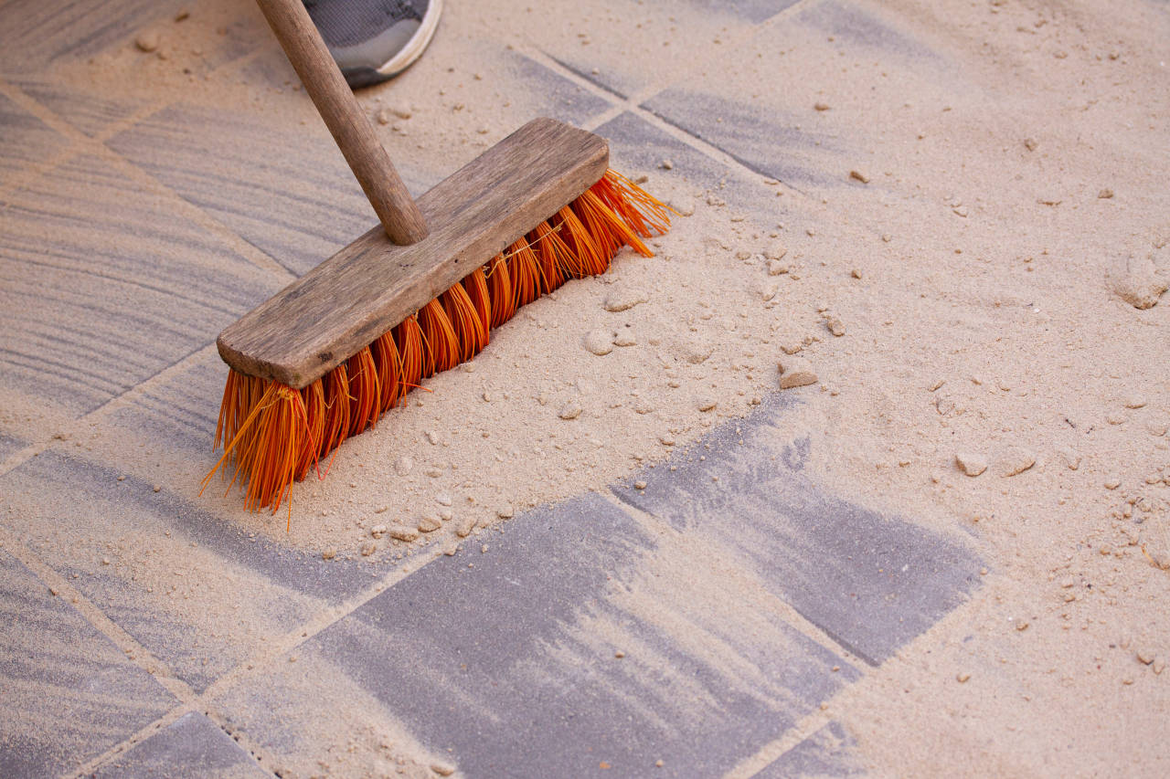 contractor spreading polymeric sand in paver joints