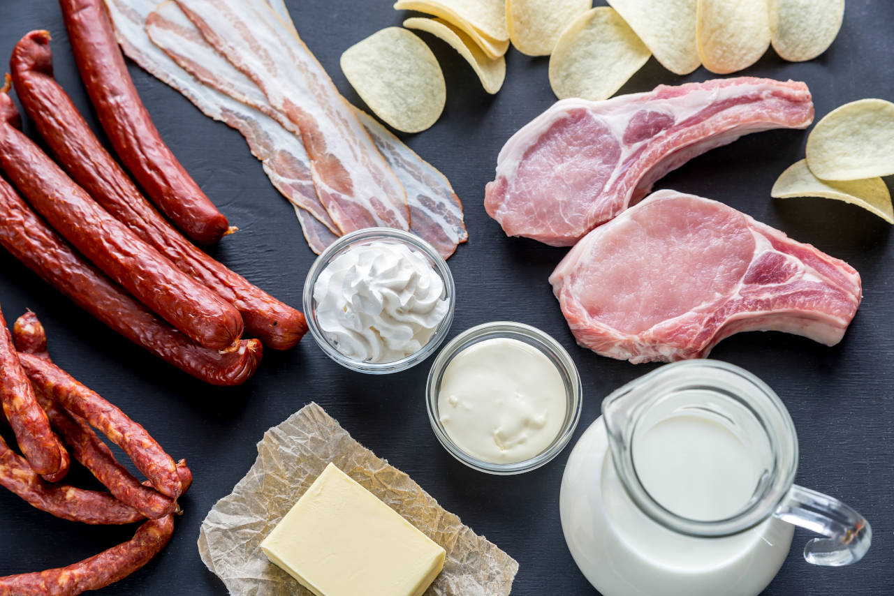 Platter of foods high in saturated fats, including butter, cream, vegetable oil, and lamb