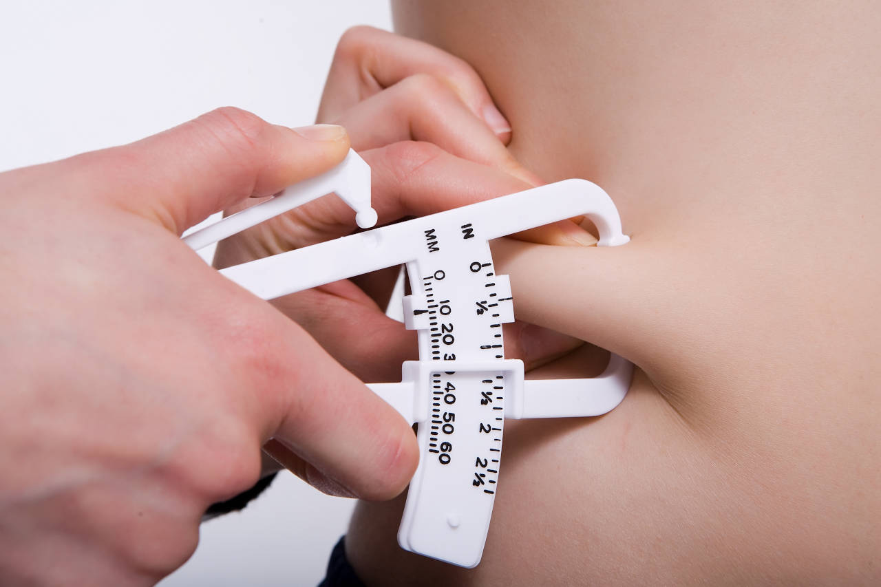 Taking a skinfold measurement with calipers to calculate body fat